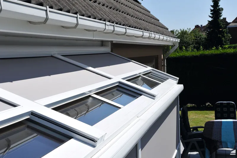 Weißes Terrassendach mit Glas, oben darauf eine Aufdachmarkise