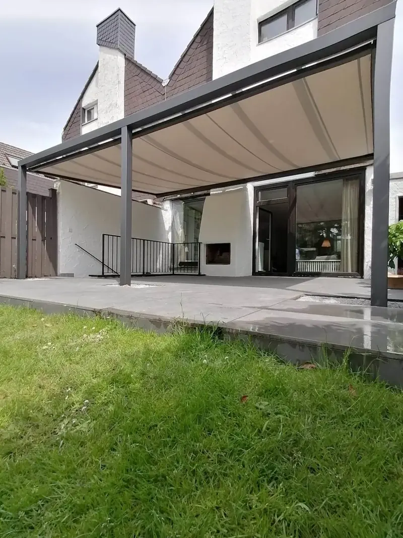 Anthrazitfarbenes Terrassendach mit heller Unterdachmarkise an einem Reihenhaus